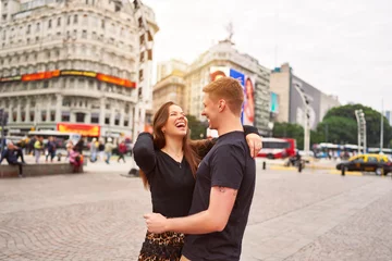 Tuinposter happy young adult heterosexual couple smiling hugging in the city of Buenos Aires © oscargutzo