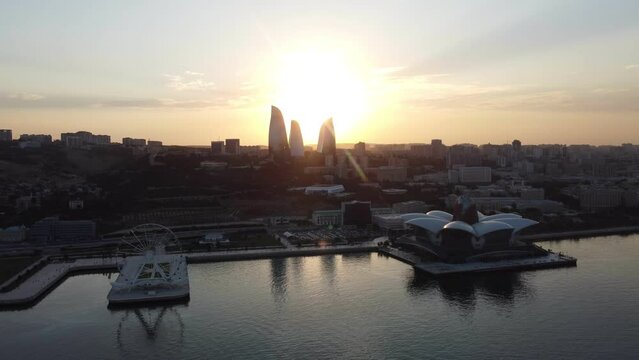 Baku, Azerbaijan - June 27, 2023: Aerial drone footage of iconic Baku landmarks: Flame Towers, Baku Eye Ferris wheel, and Deniz Mall, captured over the sea