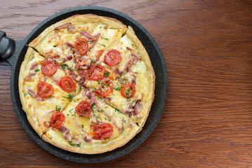 Top view of a small pizza in a dark pan on the table.