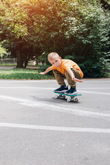 Outdoor activities for children. A cheerful young boy stays on a skateboard on the playground. Caucasian schoolboy on a walk. Front view