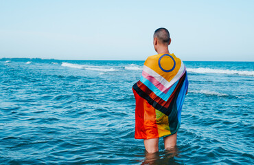wet person in the sea wrapped in a pride flag
