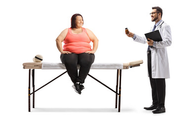 Obraz premium Overweight woman sitting on a physical therapy table and doctor showing a bottle of pills