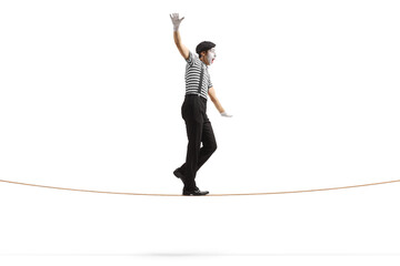 Full length profile shot of a mime walking on a tightrope