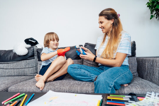 Happy mother and son playing role games with toys together in living room. Child psychotherapy process. Study in games and dialogs. Happy family. Young mother and son doing activities together at home