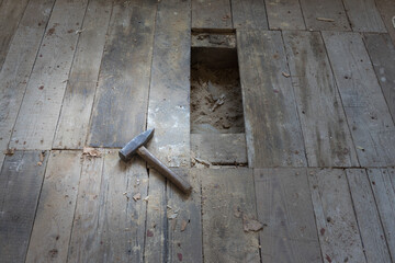 Zniszczona podłoga w starym domu z młotkiem na pierwszym planie. - obrazy, fototapety, plakaty