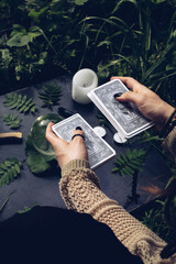 Portrait of a hippie witch girl who is in the forest and holds a deck of Tarot cards in her hands;