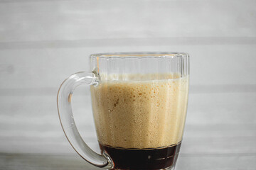 dark beer with dense foam in a glass beer mug on a light background