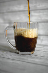 dark beer is poured into a beer mug, which stands on a light background. cooling drink