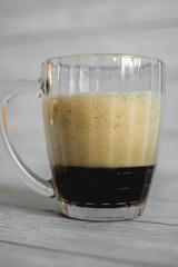 dark beer with dense foam in a glass beer mug on a light background