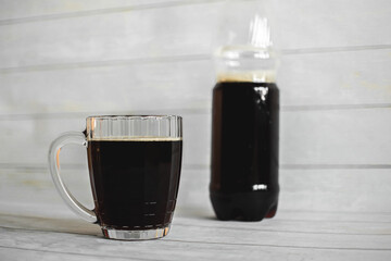 a large faceted glass mug with cold dark beer on a light background. refreshing drink