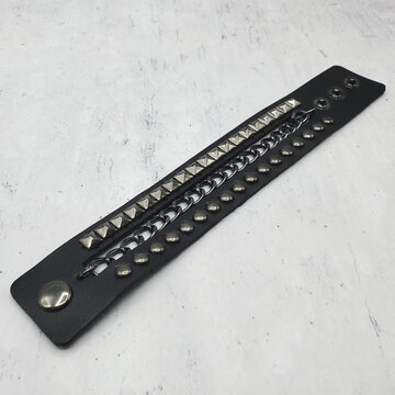 Black leather bracelet with spikes, holnitenes 
pyramid and chain. An accessory for rockers, bikers, metalheads, goths and punks. Steampunk style. Close-up subject photography.