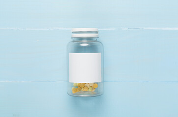 Plastic bottle with vitamins on wooden background, top view