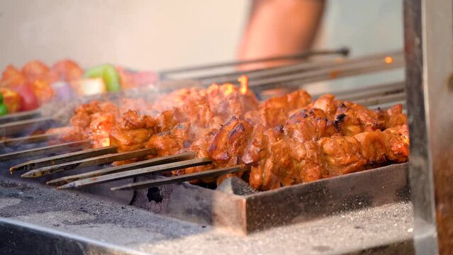 slow motion shot of tikka kebabs cooking over coal fire with smoke steam coming off showing a popular street food in delhi, lucknow india with chicken and mutton