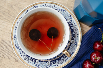 Two cherries in a cup with tea. Fruit tea, top view. Rustic style Sweet red cherries. Cherries. fruit still life
