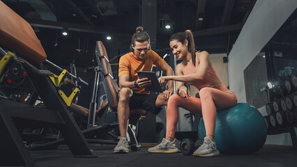 Fototapeta na wymiar Workout, Fitness workout in gym with trainer assisted in training, Fitness concept, Fit asian woman, Young white man and asian girl exercising in the gym.