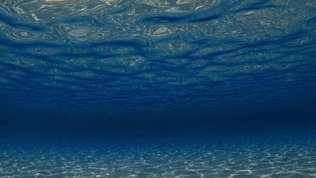 Amazing under water scene of crystalline turquoise tropical ocean water with rippled surface and reflections on seafloor with blue background. Slow motion