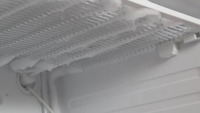 Defrosting the refrigerator from ice . Cleaning, a lot of ice and snow melts in the freezer of the refrigerator. Drops of ice are dripping. Cleaning the refrigerator. A broken household appliance.