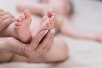 Hand of mother holding tender bare feet of infant baby lying on soft bed at home caring woman expressing love to little boy sleeping in nursery in morning closeup