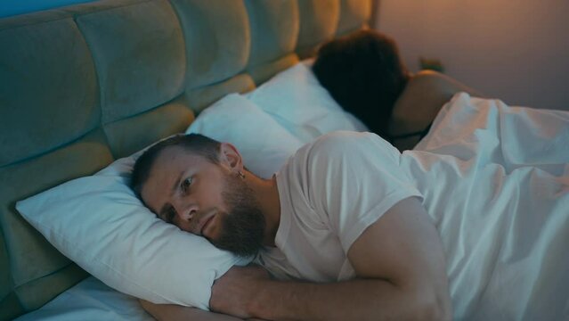 Unhappy man lying sleepless, living in unhappy marriage, infidelity or cheating