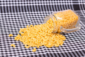 Scattered Uncooked Chifferi Rigati Pasta on Black Checkered Towel. Fat and Unhealthy Food. Classic Dry Macaroni. Italian Culture and Cuisine. Raw Pasta