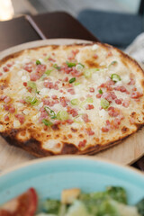 Tasty thin pizza with cubes of bacon and onions
