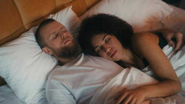 Young man suffering from sleeplessness, hugging his sleeping girlfriend, anxiety