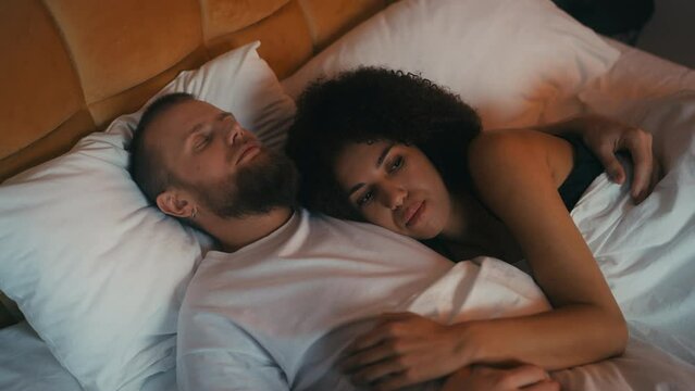 African American woman thinking about life near her sleeping husband, problems