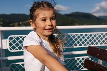 Little girl during the excursion along the lake on ship. The wind blows the hair