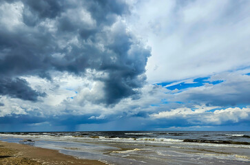 White clouds on blue sky over calm Baltic sea with sunlight reflection in sea. Nature shot in Latvia. The Latvian Coast of the Baltic Sea.	
