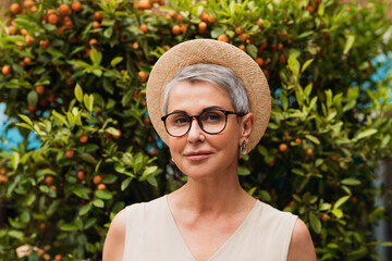 Portrait of a stylish mature woman. Senior female with gray hair wearing glasses and a small straw...