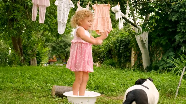 The child is washing clothes in the garden. Selective focus.