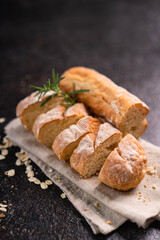 Sliced baguette bread on wooden coaster and rustic background. Artisan Sourdough bread.