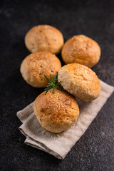 Homemade whole grain brown buns with sesame seeds on rustic background. Healthy artisan bread.