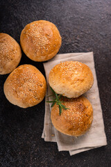 Homemade whole grain brown buns with sesame seeds on rustic background. Healthy artisan bread.