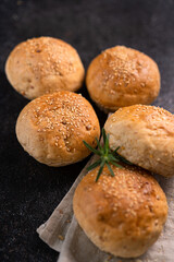 Homemade whole grain brown buns with sesame seeds on rustic background. Healthy artisan bread.