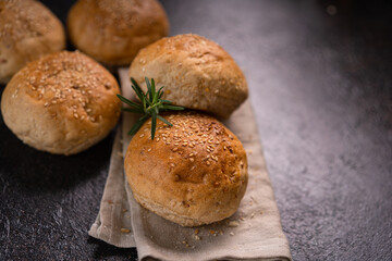 Homemade whole grain brown buns with sesame seeds on rustic background. Healthy artisan bread.