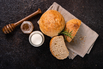 Homemade whole grain brown buns with sesame seeds on rustic background. Healthy artisan bread.