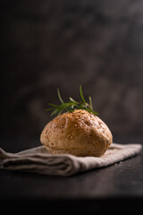 Homemade whole grain brown buns with sesame seeds on rustic background. Healthy artisan bread.
