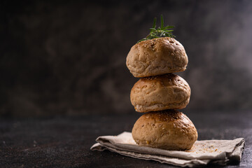 Homemade whole grain brown buns with sesame seeds on rustic background. Healthy artisan bread.