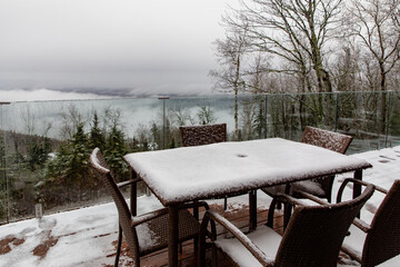 vue sur une table à quatre personnes sur un balcon à l'extérieur après avoir reçu une première neige lors d'une journée grise