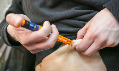 A diabetic man injecting himself with insulin before eating. Insulin injection close-up.