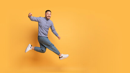 Fototapeta na wymiar Hooray. Overjoyed Young Asian Guy Jumping In Air Over Yellow Background