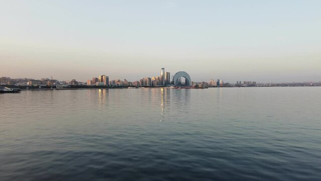 Baku, Azerbaijan - June 27, 2023: Drone footage taken at sunset, showing the magnificent Crescent Hotel and surrounding skyscrapers, with a backdrop of the stunning Baku skyline.