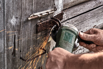 A man cuts a lock on a garage door with an angle grinder. Concept - theft of property.