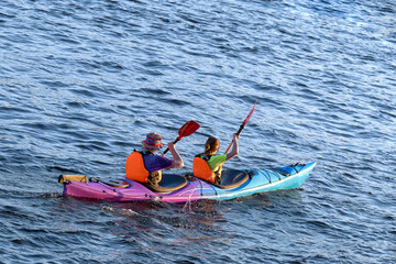 A couple of young people are kayaking on the water. Young family on active vacation.