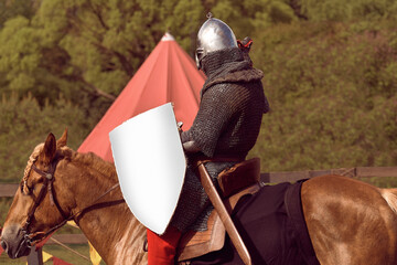 Medieval knight on a horse with a sword and shield. A man in chain mail with a weapon on horseback...