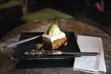 Half eaten lemon cheesecake with lime decoration, in a posh cafe.