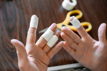 Women's hands with bandaged fingers. Safety precautions when working with hands, damage at work