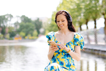Happy woman listening music in a park with headphones a sunny day near lake