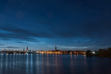 Noctilucent clouds over the Daugava river and view to Old Riga Town and stone bridge on July night. Long exposure photography.